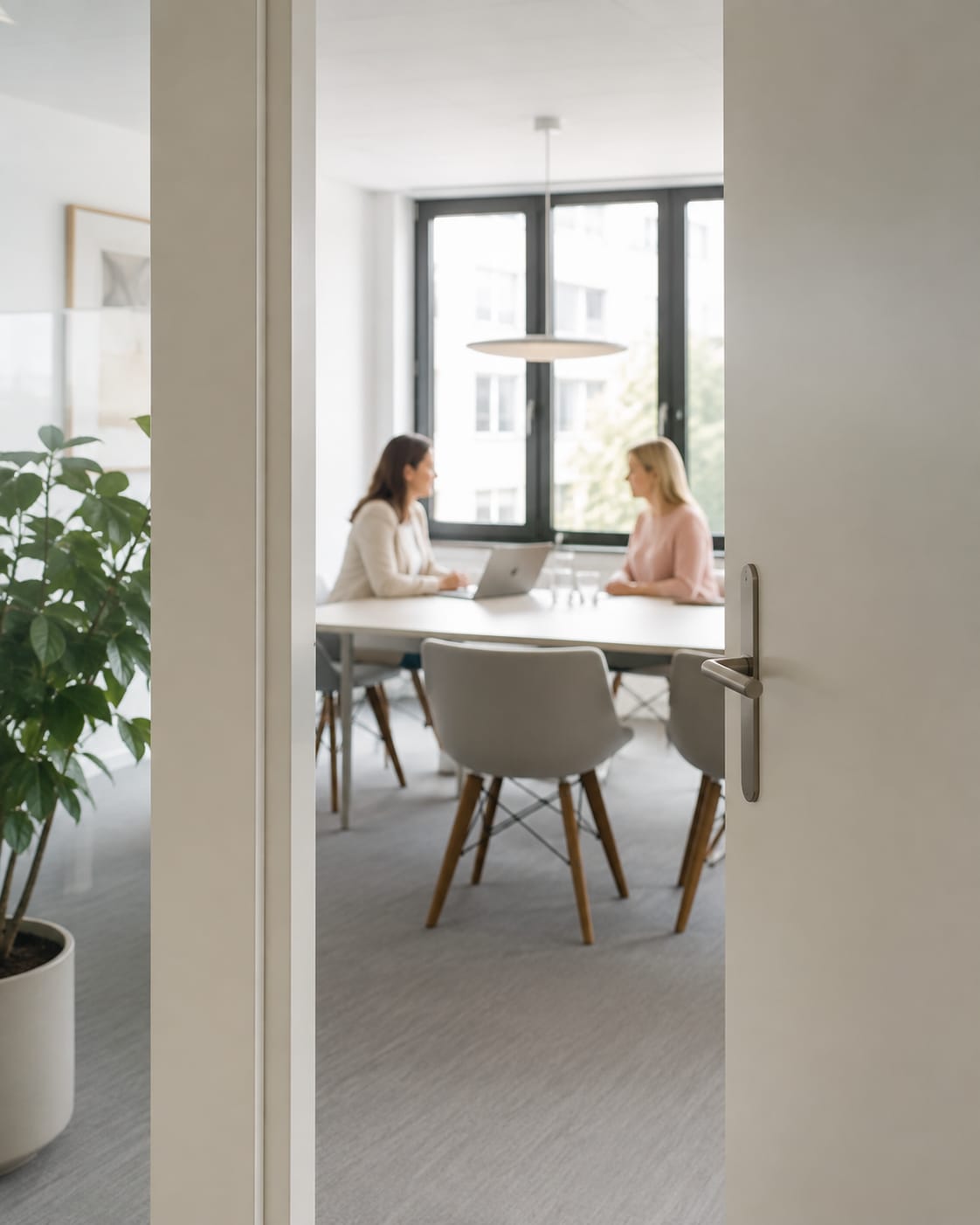 Illustration: Zwei Frauen im Gespräch an einem Besprechungstisch in einem hellen Büro